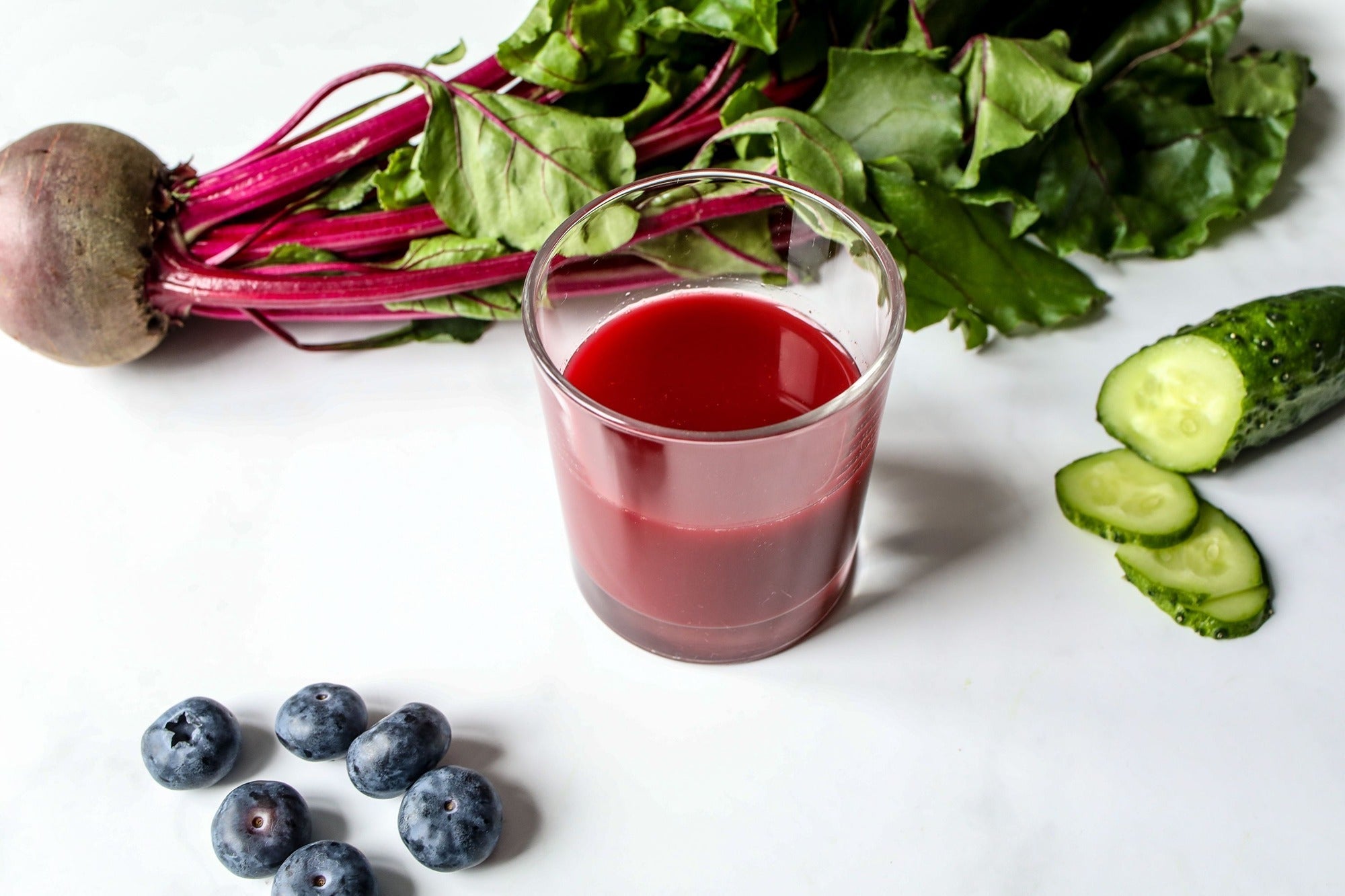 a vibrant glass of beetroot juice beside fresh beet roots